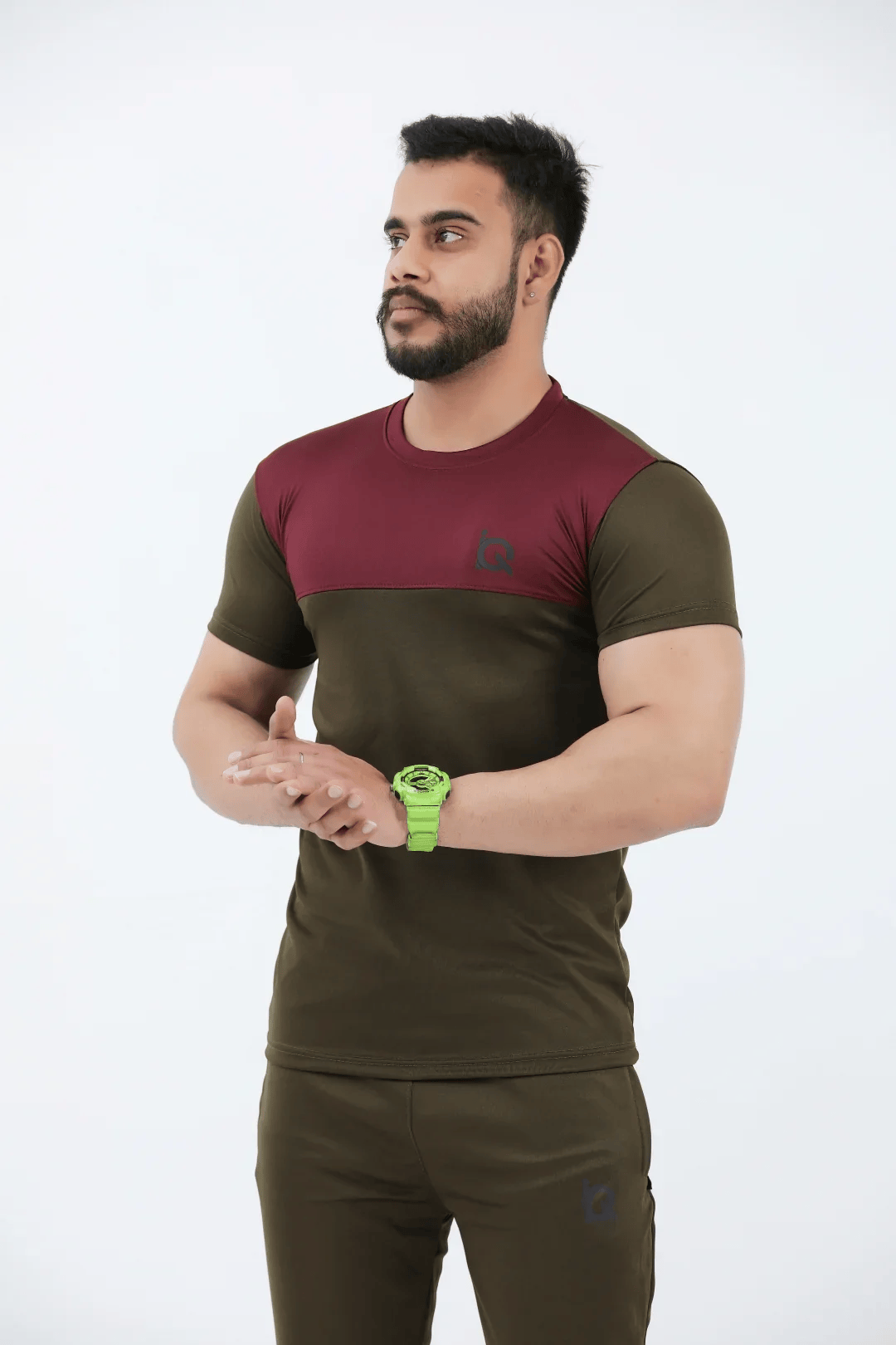 Man wearing a two-tone t-shirt and pants with a green watch on a white background